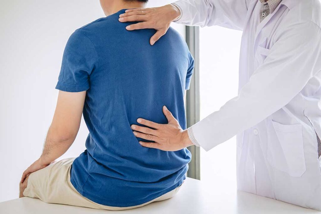 A chiropractor gently adjusting a woman’s lower back in a bright, comfortable clinic setting.