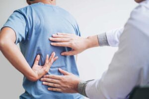 A therapist works on a patient’s back while a spine model and treatment table sit nearby.